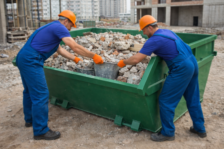 Бригада грузчиков загружает строительный мусор в контейнер